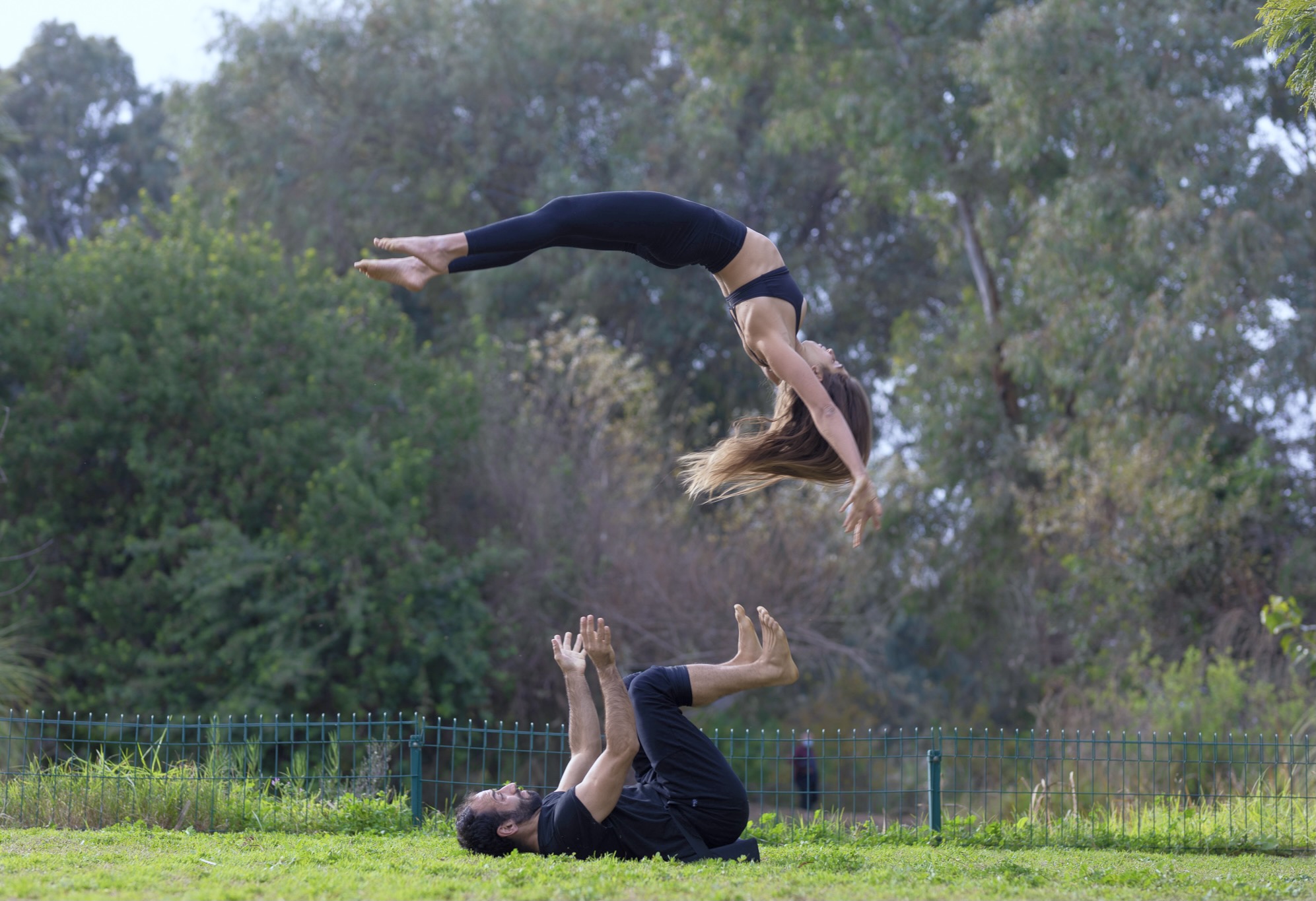 Joe basing a flyer in a deep backbend in a grassy park.